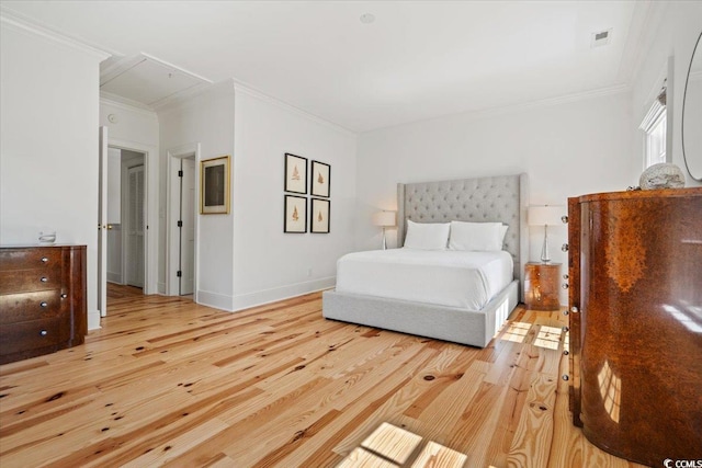 bedroom with baseboards, crown molding, attic access, and hardwood / wood-style floors