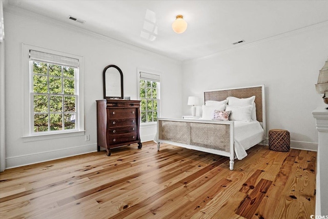 bedroom featuring ornamental molding, baseboards, visible vents, and hardwood / wood-style floors