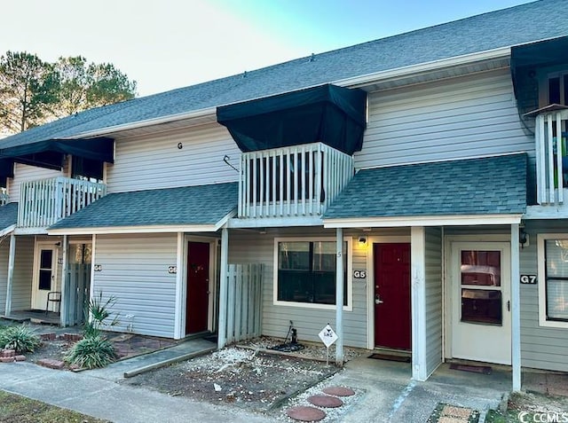 townhome / multi-family property featuring a shingled roof and a balcony