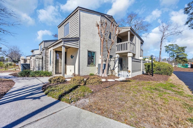 view of home's exterior featuring a balcony, fence, and stucco siding