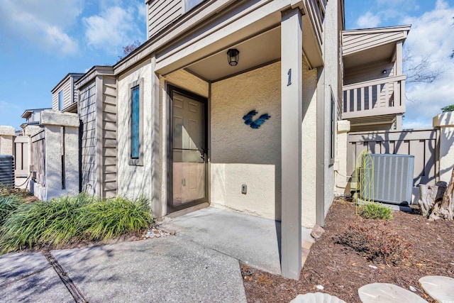 doorway to property featuring central AC and stucco siding