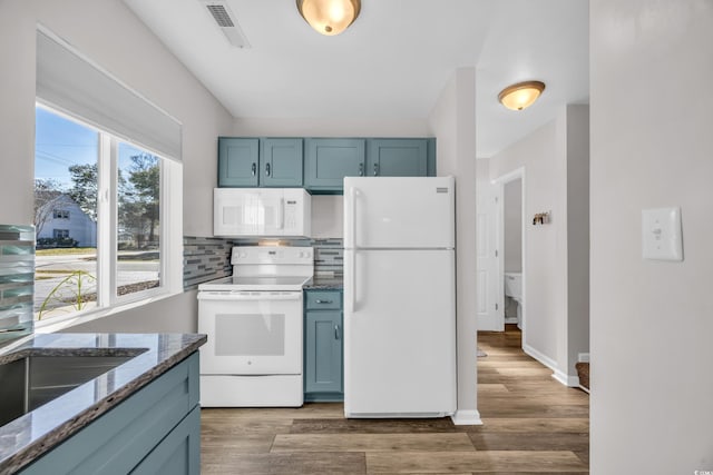 kitchen with decorative backsplash, blue cabinetry, white appliances, and dark stone counters