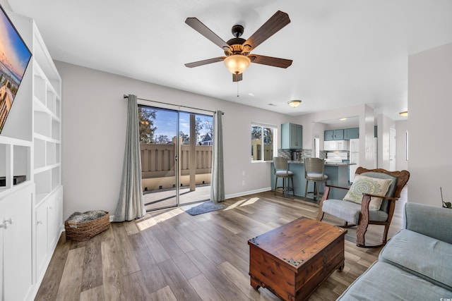 living area with wood finished floors, baseboards, and ceiling fan