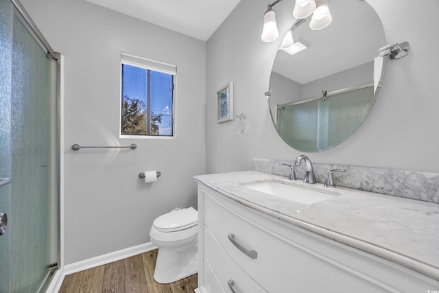 full bath with a shower stall, baseboards, toilet, wood finished floors, and vanity