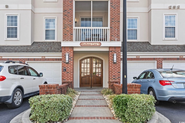 property entrance with a garage, brick siding, and roof with shingles