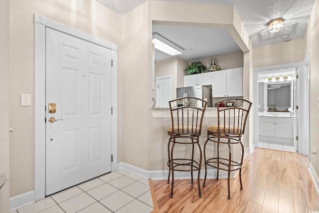 entrance foyer with light wood finished floors, baseboards, and a textured ceiling