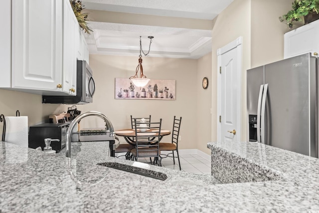 kitchen with light stone counters, light tile patterned flooring, white cabinetry, appliances with stainless steel finishes, and a raised ceiling