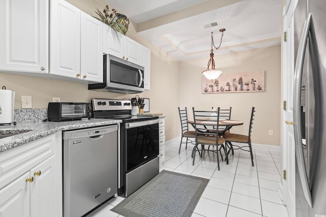 kitchen featuring white cabinets, appliances with stainless steel finishes, hanging light fixtures, a tray ceiling, and light tile patterned flooring