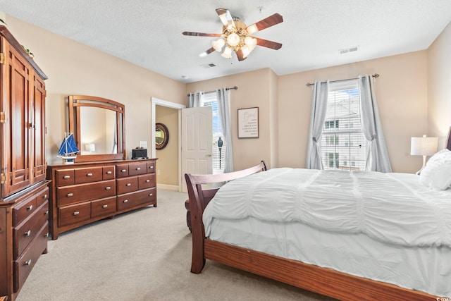 bedroom featuring visible vents, ceiling fan, light carpet, and a textured ceiling