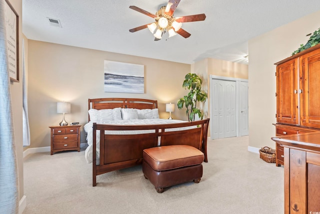 bedroom featuring baseboards, visible vents, light colored carpet, a textured ceiling, and a closet