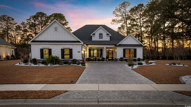 view of front of home with a shingled roof, decorative driveway, and board and batten siding