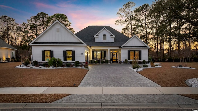 view of front of house with decorative driveway, board and batten siding, and a shingled roof