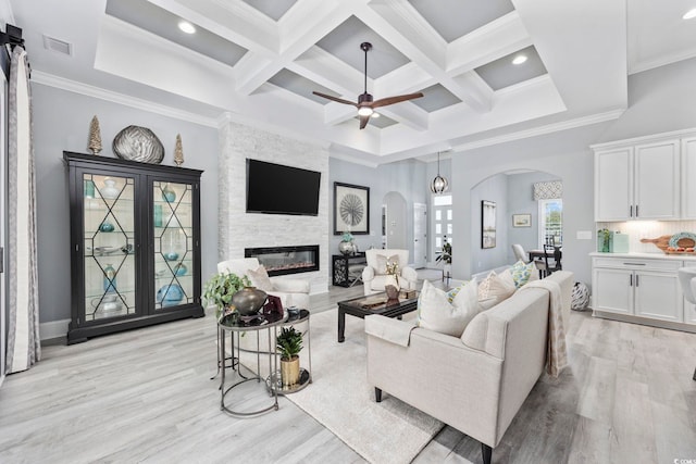 living area with arched walkways, a large fireplace, coffered ceiling, visible vents, and light wood-type flooring