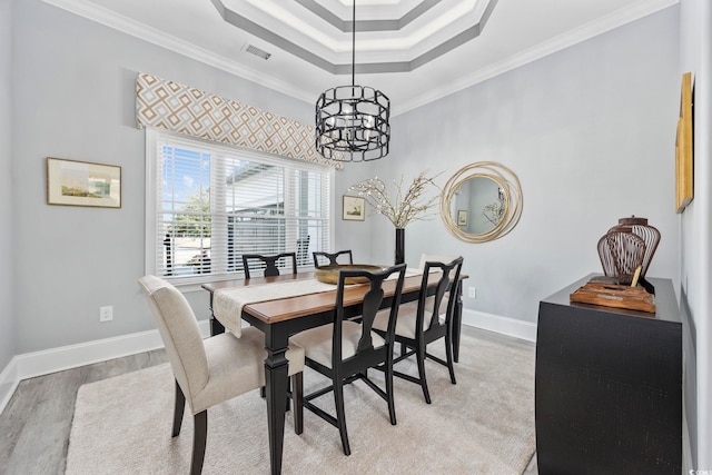 dining area featuring visible vents, baseboards, light wood-style floors, a tray ceiling, and crown molding