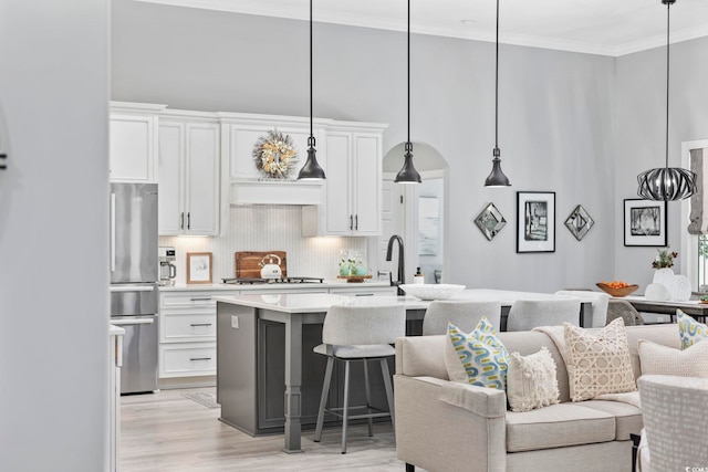 kitchen with gas stovetop, open floor plan, light countertops, freestanding refrigerator, and crown molding