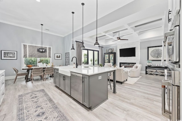 kitchen featuring coffered ceiling, gray cabinetry, stainless steel dishwasher, a fireplace, and a sink