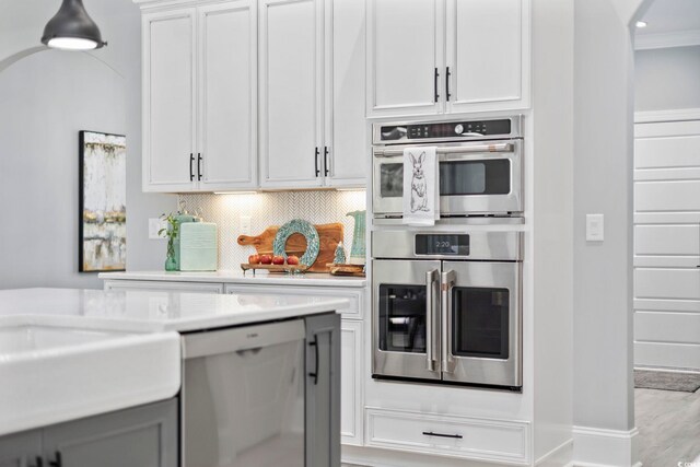 kitchen featuring crown molding, light countertops, appliances with stainless steel finishes, and tasteful backsplash