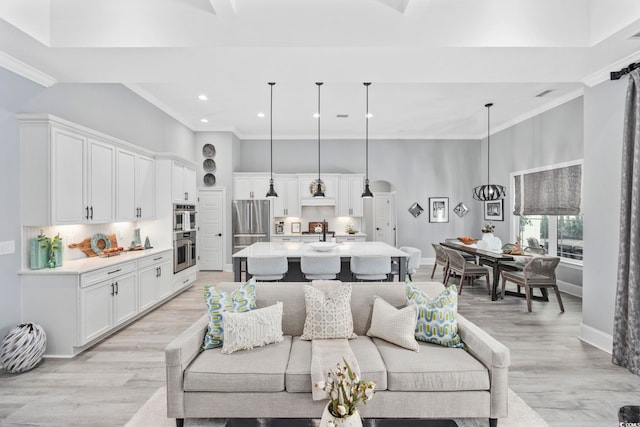 living room featuring crown molding, light wood finished floors, and a high ceiling