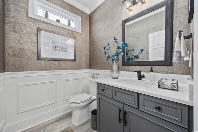 bathroom featuring crown molding, toilet, wainscoting, vanity, and wood finished floors