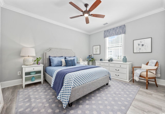 bedroom with light wood-style flooring, visible vents, baseboards, and crown molding