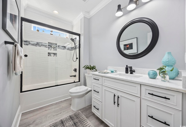 bathroom featuring toilet, ornamental molding, wood finished floors, combined bath / shower with glass door, and vanity