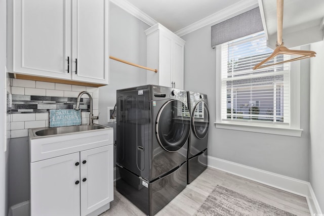 laundry room with washing machine and dryer, a sink, light wood-style floors, ornamental molding, and cabinet space