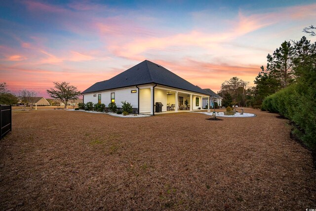 back of house at dusk with a patio area