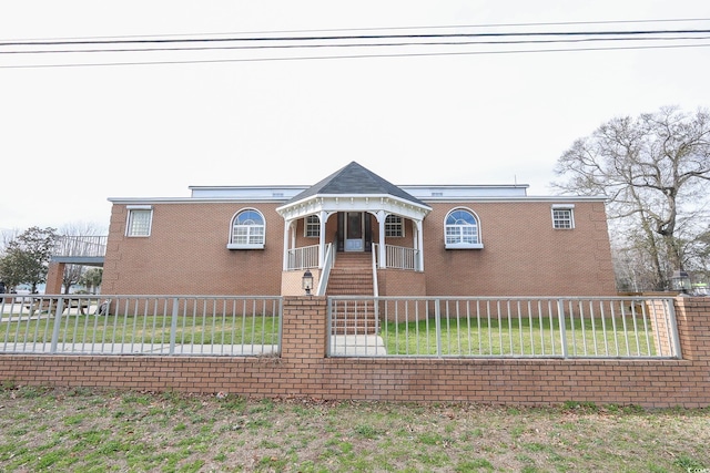 view of front facade with covered porch, brick siding, and a fenced front yard