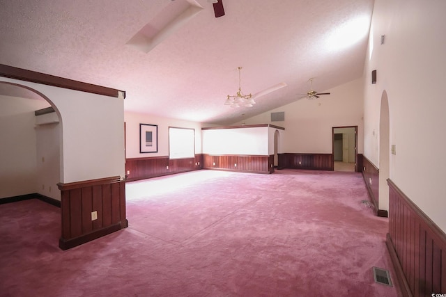 interior space with visible vents, arched walkways, wainscoting, a textured ceiling, and ceiling fan with notable chandelier