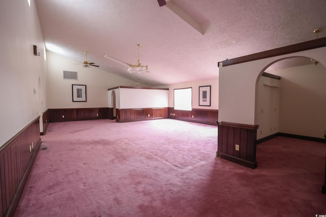 interior space with arched walkways, lofted ceiling, wainscoting, a textured ceiling, and ceiling fan with notable chandelier