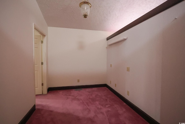 carpeted empty room featuring baseboards and a textured ceiling