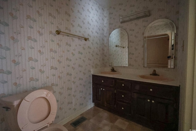 bathroom featuring double vanity, wallpapered walls, visible vents, and a sink