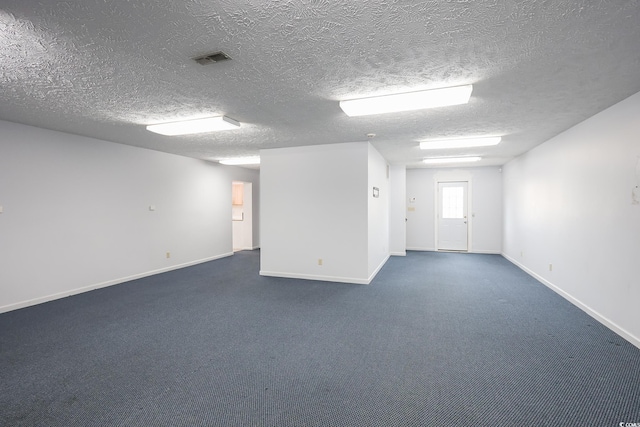 unfurnished room featuring dark colored carpet, visible vents, a textured ceiling, and baseboards