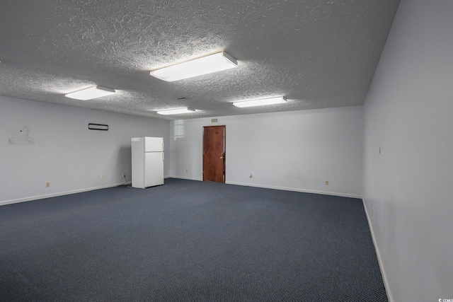 spare room featuring baseboards, dark colored carpet, and a textured ceiling