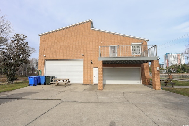 view of home's exterior featuring a garage, brick siding, and a balcony