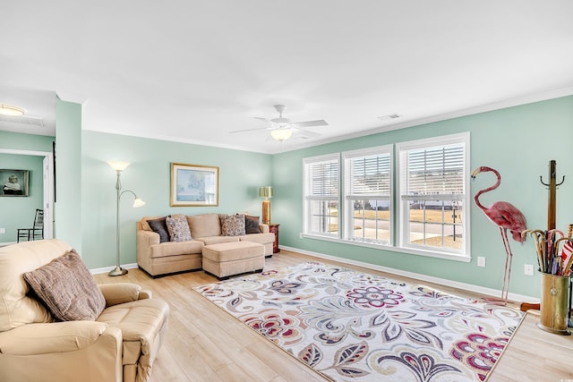 living room with ornamental molding, visible vents, baseboards, and wood finished floors