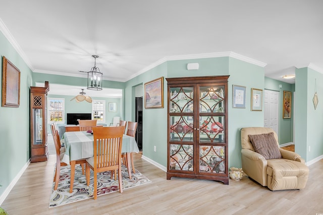 dining area with light wood finished floors, a notable chandelier, baseboards, and crown molding