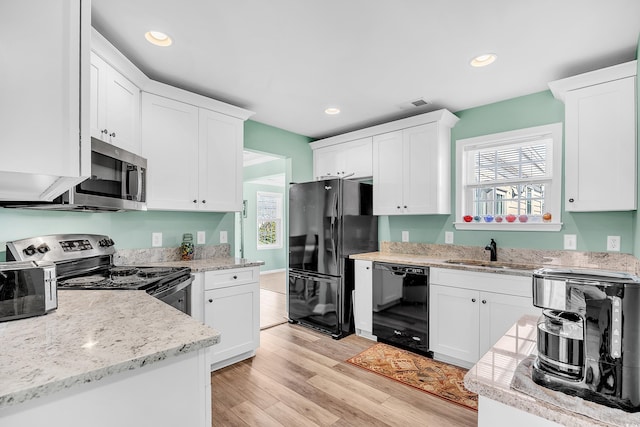 kitchen with recessed lighting, white cabinets, a sink, light wood-type flooring, and black appliances