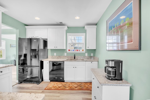 kitchen with white cabinetry, a sink, and black appliances