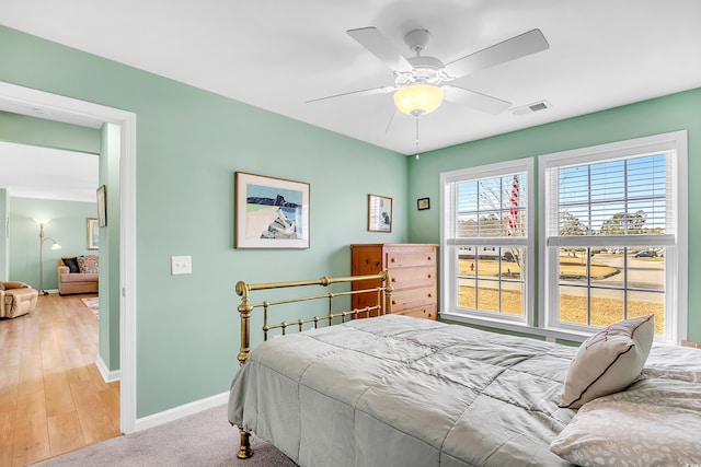 bedroom featuring light carpet, ceiling fan, visible vents, and baseboards