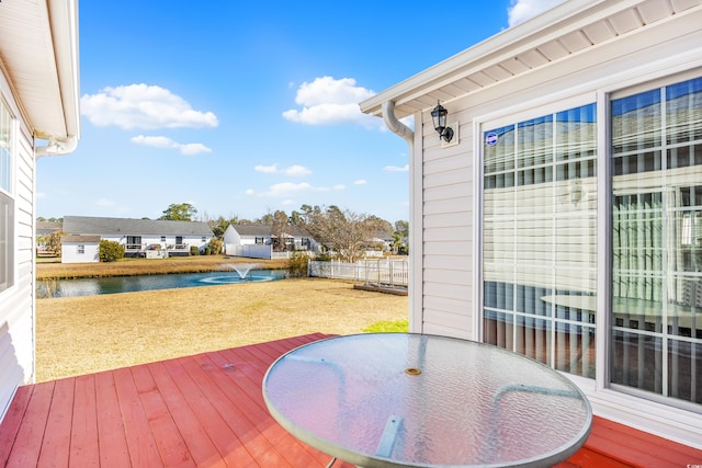 deck featuring a water view, outdoor dining area, and a yard