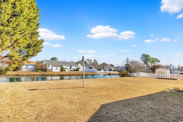 view of yard featuring a water view, fence, and a residential view