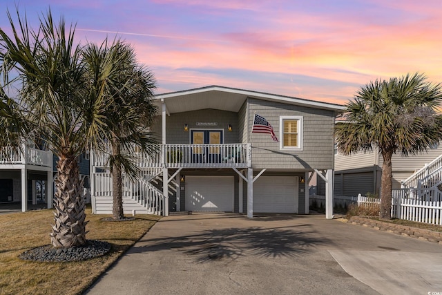 view of front of home featuring an attached garage, covered porch, driveway, and stairway