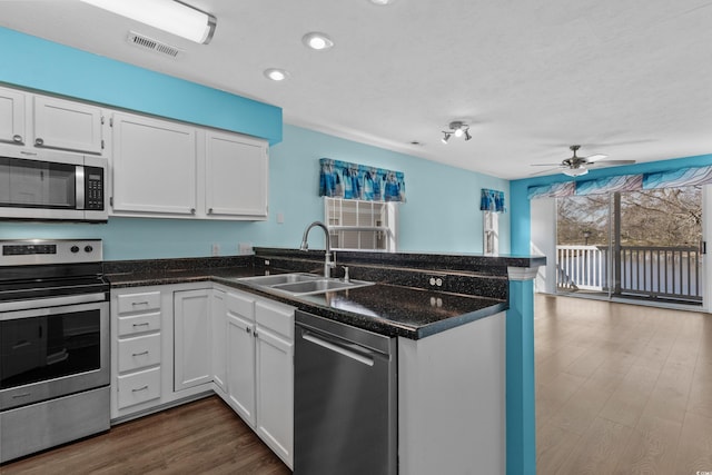 561 White River Dr Unit 11-D, Myrtle Beach, SC 29579 - kitchen featuring appliances with stainless steel finishes, a sink, a peninsula, white cabinetry, and dark wood-style floors