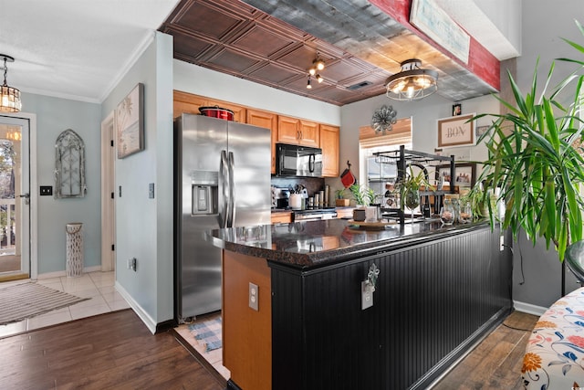 kitchen featuring wood finished floors, baseboards, black microwave, and stainless steel fridge with ice dispenser