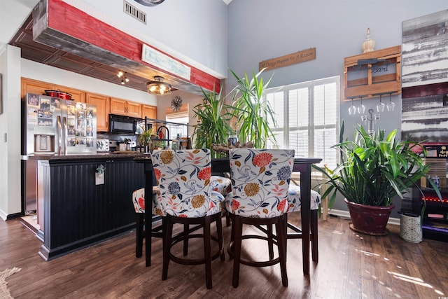 dining room featuring visible vents, baseboards, a high ceiling, and dark wood-style flooring