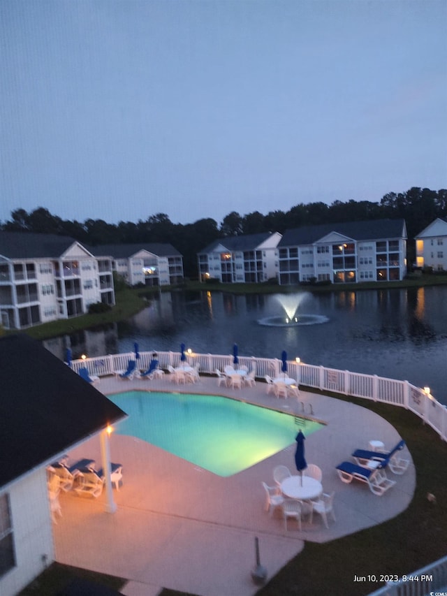 community pool featuring a water view, a patio, and fence