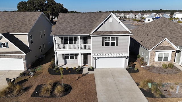 view of front of property with concrete driveway, a balcony, a residential view, an attached garage, and board and batten siding