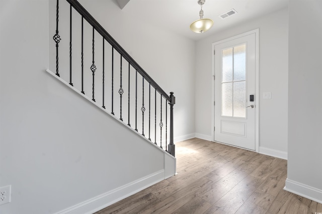 entrance foyer with stairs, wood finished floors, visible vents, and baseboards