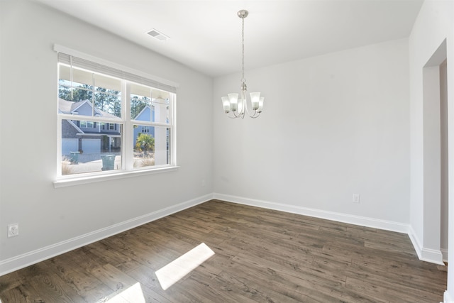 empty room featuring a notable chandelier, baseboards, visible vents, and dark wood-type flooring